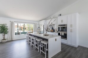 A modern kitchen with a central island, bar stools, white cabinetry, and a large window. - Old Town Fashion-pool-putting Green-bbq Grill (Scottsdale)