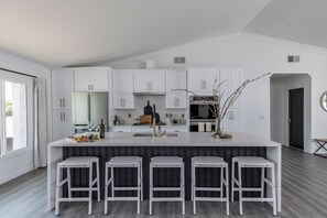 A modern kitchen with white cabinetry, a central island with bar stools, and a large window. - Old Town Fashion-pool-putting Green-bbq Grill (Scottsdale)