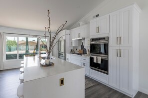 A modern kitchen with white cabinetry, stainless steel appliances, and a central island. - Old Town Fashion-pool-putting Green-bbq Grill (Scottsdale)