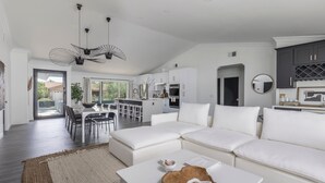 Un salon spacieux avec un canapé blanc, une table basse et un coin repas comprenant une table et des chaises blanches.