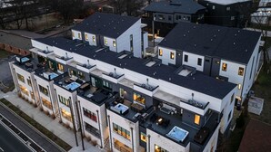 Un immeuble résidentiel moderne à plusieurs étages, doté de terrasses sur le toit, de grandes fenêtres et d’une toiture plate.