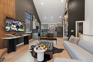 Una sala de estar moderna con un televisor grande, un comedor y una cocina.