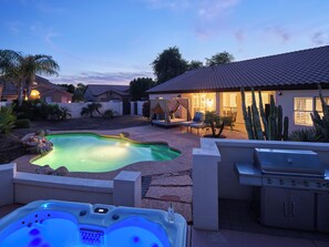 A backyard with a swimming pool, hot tub, and barbecue grill.