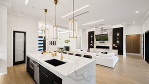 A modern kitchen with a marble island, black cabinets, and gold fixtures. - Havana - Walk to Old Town - Heated Pool & Spa (Scottsdale)