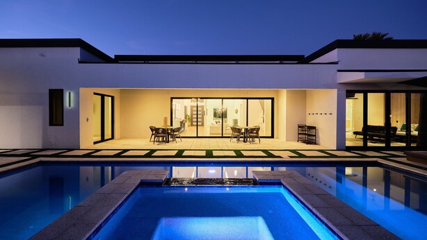 A modern house with a swimming pool, a dining area with chairs and a table, and a large sliding glass door leading to an interior space. - Havana - Walk to Old Town - Heated Pool & Spa (Scottsdale)
