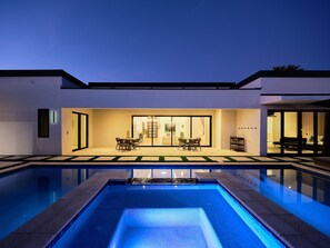 A modern house with a swimming pool, a dining area with chairs and a table, and a large sliding glass door leading to an interior space. - Havana - Walk to Old Town - Heated Pool & Spa (Scottsdale)