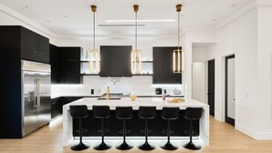 A modern kitchen with a central island, black bar stools, stainless steel appliances, and pendant lighting. - Havana - Walk to Old Town - Heated Pool & Spa (Scottsdale)