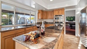 A modern kitchen with granite countertops, wooden cabinets, stainless steel appliances, and a large window providing natural light. - Kierland Charm - Private Yard w/ Pool, Golf & More (Scottsdale)
