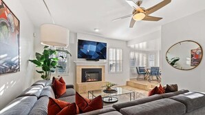 A modern living room with a sofa set, a fireplace, a flat-screen TV, and a ceiling fan. - Kierland Charm - Private Yard w/ Pool, Golf & More (Scottsdale)