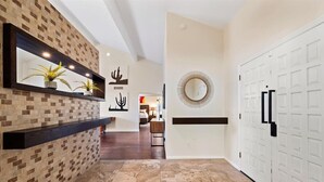 A hallway with a tiled floor, a brick accent wall, a mirror, and a white door. - Kierland Charm - Private Yard w/ Pool, Golf & More (Scottsdale)