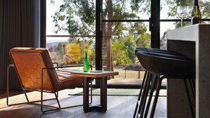 A modern room with a view of trees and hills, a brown leather chair, a small table with a green bottle, and a bar area. - Glenlyon Church - Award Winning Church Conversion (Glenlyon)