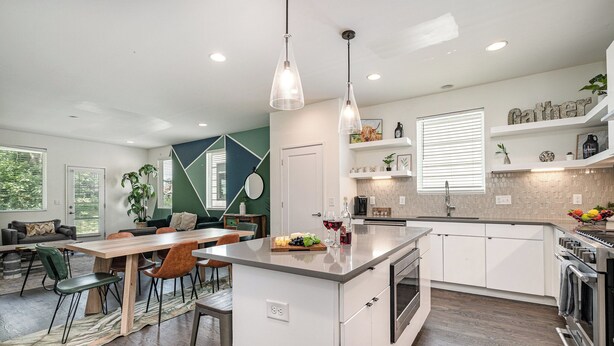 A modern kitchen with white cabinets, a central island, and pendant lighting. - Verde Heights-sleeps 12-in Cumberland Heights (Nashville)