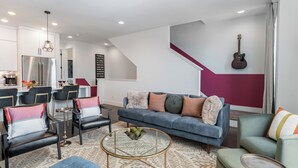Un salon moderne comprenant un canapé, des fauteuils, une table basse et un coin cuisine avec un réfrigérateur.