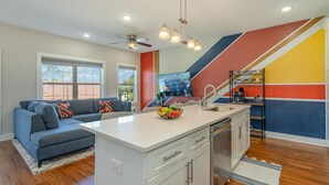 Una cocina moderna con una isla central, armarios blancos y una pared de acento colorida.