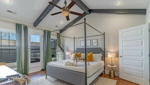 Un dormitorio con cama con dosel, ventilador de techo y vistas al exterior a través de un ventanal.