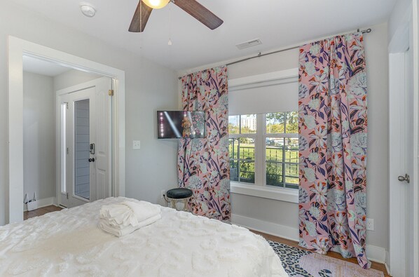A bedroom with a bed, a ceiling fan, a TV mounted on the wall, and a window with curtains. - Palette - Private Patio - Mins to Nashville Zoo (Nashville)