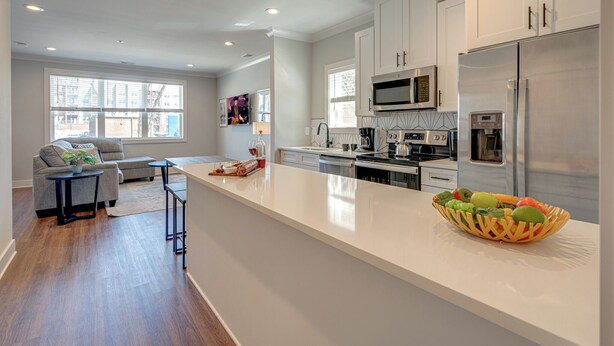 A modern kitchen with white cabinets, stainless steel appliances, and a large island. - Merry Melrose -mins to Broadway- Sleeps 6 (Nashville)