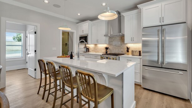 Una cocina moderna con una isla central, electrodomésticos de acero inoxidable e iluminación colgante.