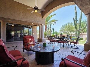 A covered patio area with a round table, red chairs, and a ceiling fan. - Valley View Villa - Private Pool - Hidden Bedroom (Scottsdale)