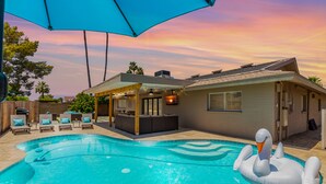 A backyard with a swimming pool, a swan inflatable, and a covered patio area. - Blue Tides Getaway - Private Pool & Fire Pit (Scottsdale)