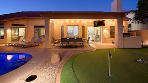 Ein Haus mit Swimmingpool, Terrasse und Outdoor-Möbeln sowie einem Putting-Green.
