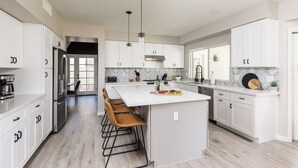 A modern kitchen with white cabinetry, a large island, and bar stools. - Sereno - Sparkling Pool - Near Scottsdale Quarter (Scottsdale)