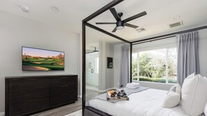 A modern bedroom with a large bed, a ceiling fan, a TV on the wall, and a view of the outdoors. - Sereno - Sparkling Pool - Near Scottsdale Quarter (Scottsdale)