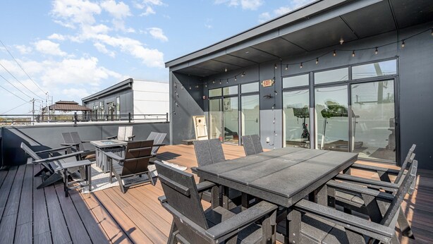 A rooftop deck with outdoor seating, a glass wall, and an exit sign. - Gallatin Retreat-private Balcony-in East Nashville (Nashville)