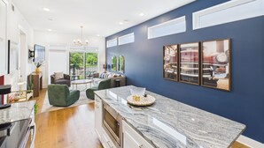 A modern kitchen with a marble countertop, a dining area with a table and chairs, and a view of the outdoors. - Gallatin Retreat-private Balcony-in East Nashville (Nashville)