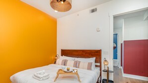 A neatly made bed with a tray of breakfast items, a bedside lamp, and a small table with a basket. - Gallatin Retreat-private Balcony-in East Nashville (Nashville)