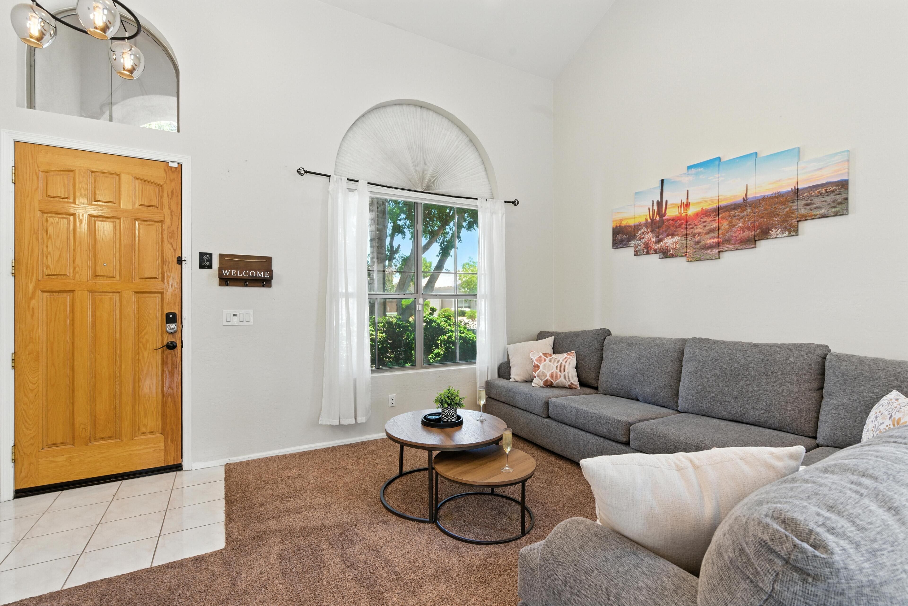 A modern living room with a grey sofa, a round coffee table, and a painting on the wall.