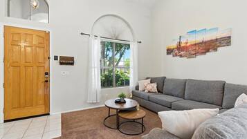A modern living room with a grey sofa, a round coffee table, and a painting on the wall.