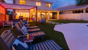 Un jardin avec un patio couvert, un espace salon extérieur et une piscine.