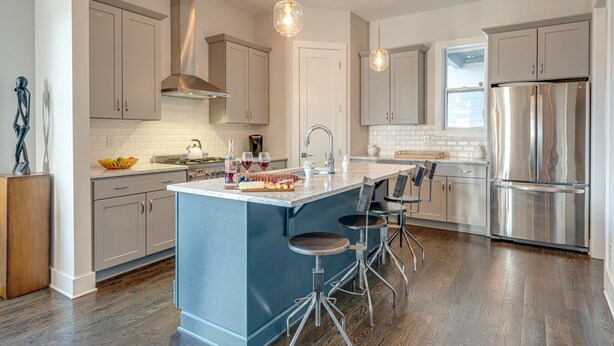 A modern kitchen with a central island, stainless steel appliances, and pendant lighting.