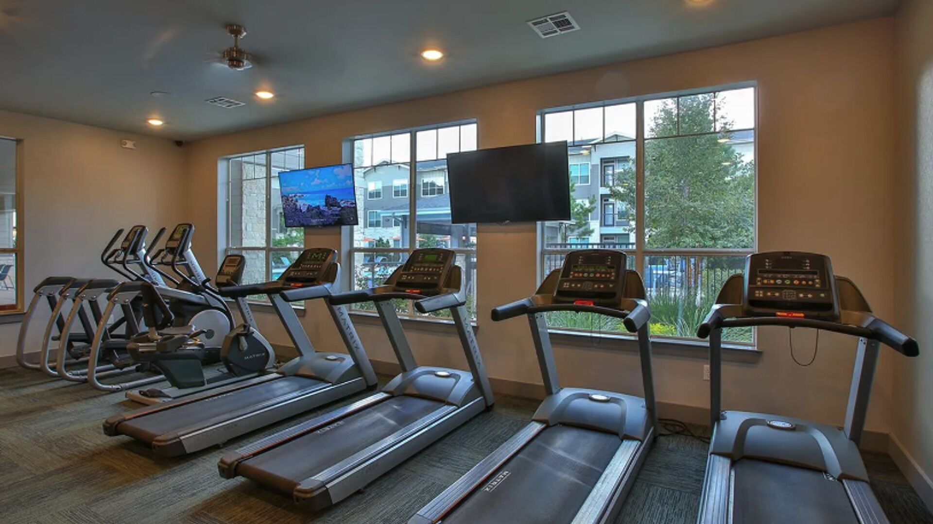 Ett gym med löpband, motionscyklar och en tv-skärm.