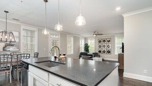 A modern kitchen with a large island, white cabinetry, and pendant lighting.