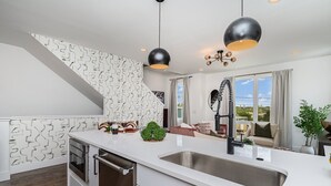 A modern kitchen with a large island, stainless steel sink, and pendant lighting. - Revival-rooftop Deck/hot Tub- Mins to Broadway (Nashville)