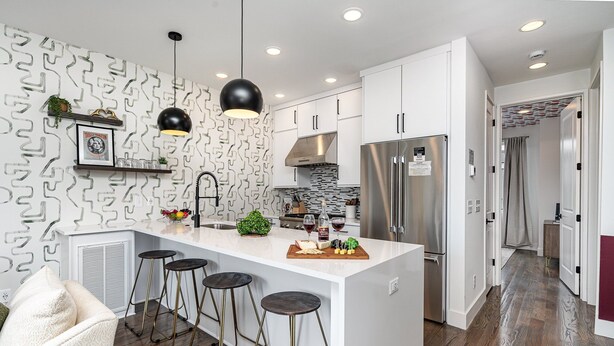 A modern kitchen with white cabinetry, a central island with stools, pendant lighting, and a stainless steel refrigerator. - Revival-rooftop Deck/hot Tub- Mins to Broadway (Nashville)