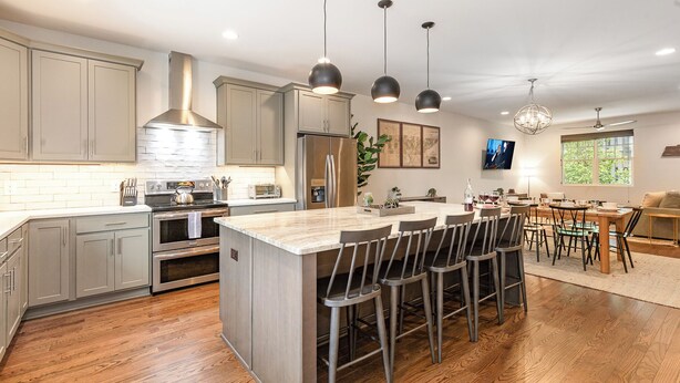 A modern kitchen with a central island, stainless steel appliances, and pendant lighting.