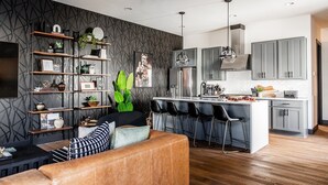 A modern kitchen with a central island, bar stools, and a seating area with a sofa and coffee table. - Heart of Gulch - 4 Min to Broadway - Designer Home (Nashville)