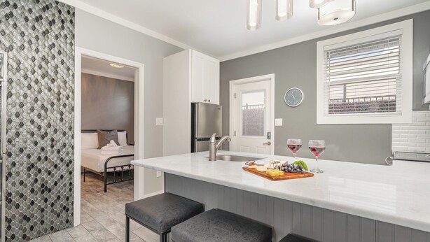 A modern kitchen with a central island, a built-in refrigerator, and a window with blinds. - Lucent Pearl - Private Patio - Near Broadway (Nashville)