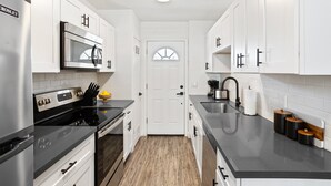 A modern kitchen with white cabinets, stainless steel appliances, and a black countertop. - Dawn - Walk to Old Town & Entertainment District (Scottsdale)