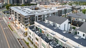 Ein modernes Wohngebäude in der Stadt mit mehreren Etagen, großen Fenstern und einer Dachterrasse.