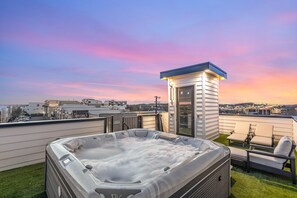 A rooftop with a hot tub, lounge chairs, and a small tower-like structure.