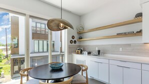 Een moderne keuken met witte kastjes, een ronde eettafel en een hangende hanglamp.