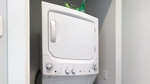 A compact, white front-loading washer and dryer unit with a control panel featuring multiple settings and knobs. - Country Lyric - Mins to Downtown - Rooftop Deck (Nashville)