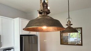 A kitchen with a stainless steel refrigerator, a coffee maker on the counter, and a pendant light fixture. - Country Lyric - Mins to Downtown - Rooftop Deck (Nashville)