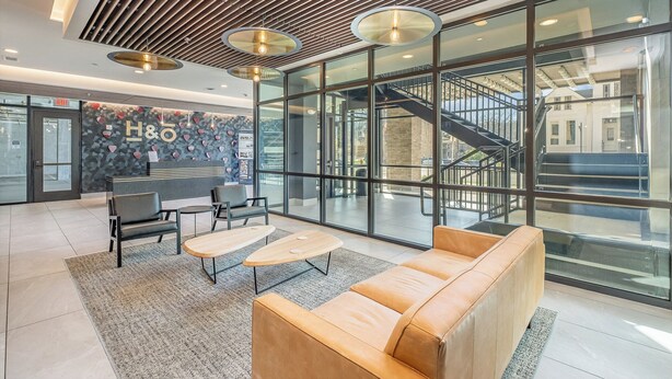 A modern lobby with a sofa, two tables, and a staircase leading to upper floors. - Treble Maker -rooftop Lounge - Pool - In Music Row (Nashville)