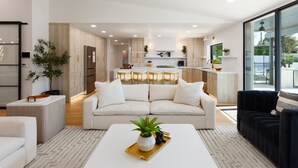 Een moderne woonkamer met een bank, salontafel en een keuken op de achtergrond.