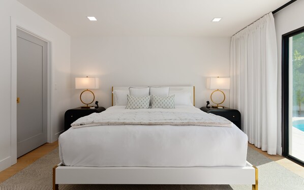 Une chambre moderne avec un grand lit, deux tables de chevet avec des lampes, une tête de lit et une vue sur une piscine, visible à travers une grande fenêtre.